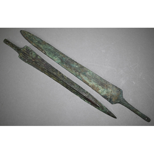 1100 - A Bronze Age dagger blade with shallow diamond section, 25 cm and a plainer 29 cm example, to/w a sp... 