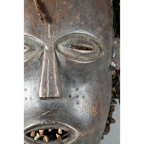 1112 - A West African Dan tribe mask, Deangle, Ivory Coast or Liberia, the carved oval stained hardwood fac... 