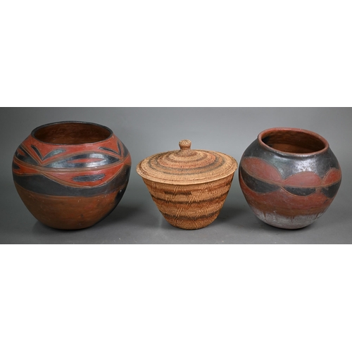 1120 - Two African terracotta cooking pots with incised and painted decoration, 24/21 cm diam to/w a woven ... 