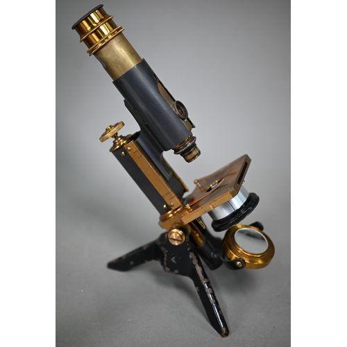 1129 - A lacquered brass microscope in case with magnifier on stand and other accessories, spare lenses etc