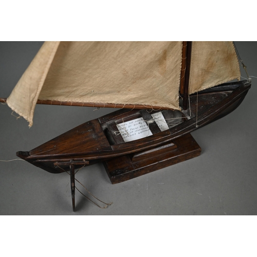 1179 - A model sailing dinghy, with card inscribed 'Model of Malay 'Dukone' made by Dick the Malay Pilot, C... 