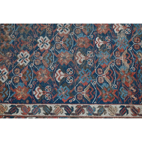 1213 - An antique Kurdish rug, the blue ground with repeating stylized geometric floral design, heavily wor... 