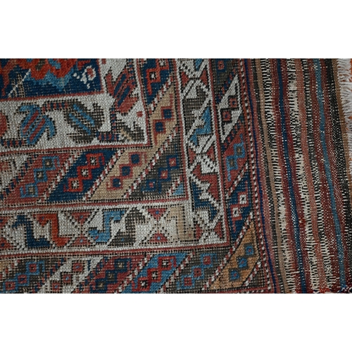 1213 - An antique Kurdish rug, the blue ground with repeating stylized geometric floral design, heavily wor... 