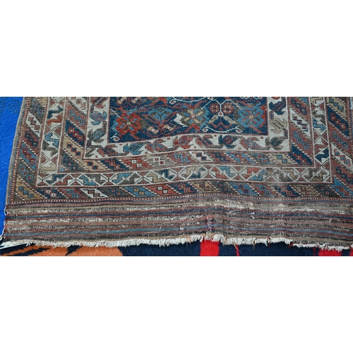 1213 - An antique Kurdish rug, the blue ground with repeating stylized geometric floral design, heavily wor... 