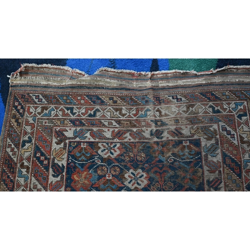 1213 - An antique Kurdish rug, the blue ground with repeating stylized geometric floral design, heavily wor... 