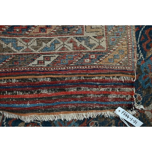 1213 - An antique Kurdish rug, the blue ground with repeating stylized geometric floral design, heavily wor... 