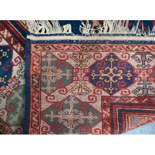 1216 - An old Turkish Caucasian design carpet  blue ground with three red ground lozenges with conforming w... 