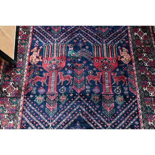 1217 - A Persian Hamadan rug, dark blue ground with repeating design of stylized goblets flanked by dogs, 2... 