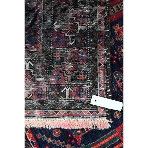 1217 - A Persian Hamadan rug, dark blue ground with repeating design of stylized goblets flanked by dogs, 2... 