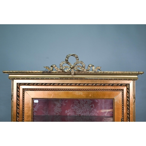 844 - A Napoleon III style giltwood three quarter glazed display cabinet surmounted by a ribbon bow mouldi... 