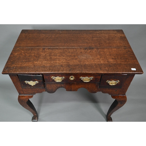 848 - An 18th century oak three drawer side table with fret cut apron raised on four square cabriole legs,... 