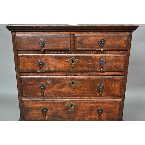 853 - A diminutive George II country oak chest on stand, with two short over three long graduated drawers,... 