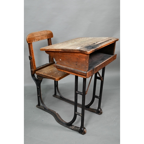 893 - A Victorian cast iron and oak student/school desk, the slope top carved with multiple graffiti, rais... 