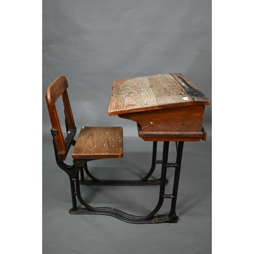 893 - A Victorian cast iron and oak student/school desk, the slope top carved with multiple graffiti, rais... 