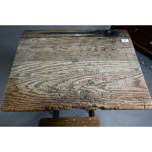 893 - A Victorian cast iron and oak student/school desk, the slope top carved with multiple graffiti, rais... 