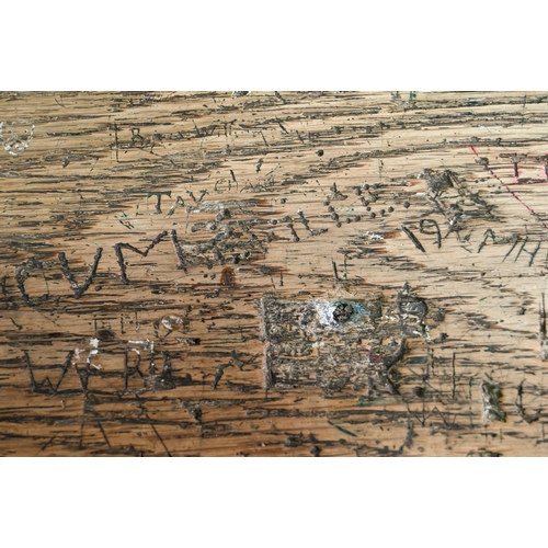 893 - A Victorian cast iron and oak student/school desk, the slope top carved with multiple graffiti, rais... 