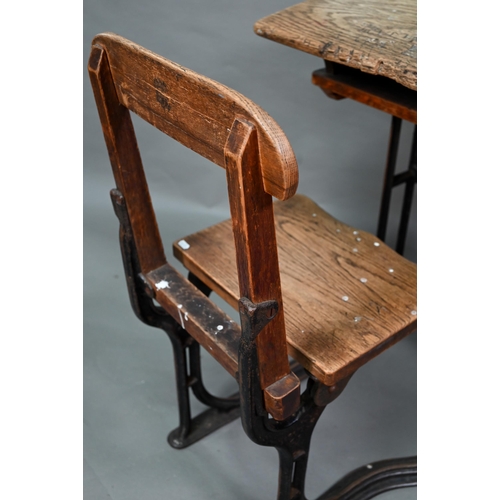 893 - A Victorian cast iron and oak student/school desk, the slope top carved with multiple graffiti, rais... 