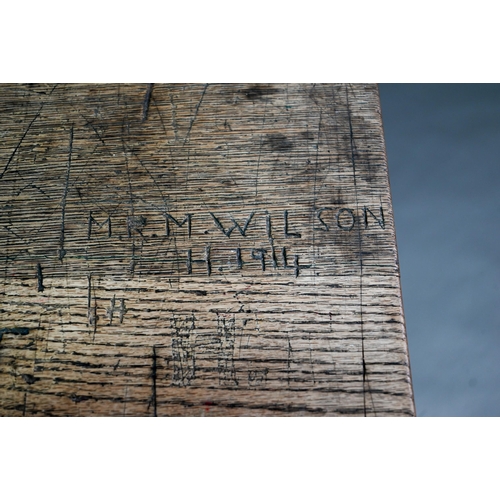 894 - A Victorian cast iron and oak student/school desk, the slope top carved with multiple graffiti, rais... 