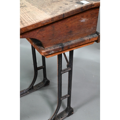 894 - A Victorian cast iron and oak student/school desk, the slope top carved with multiple graffiti, rais... 