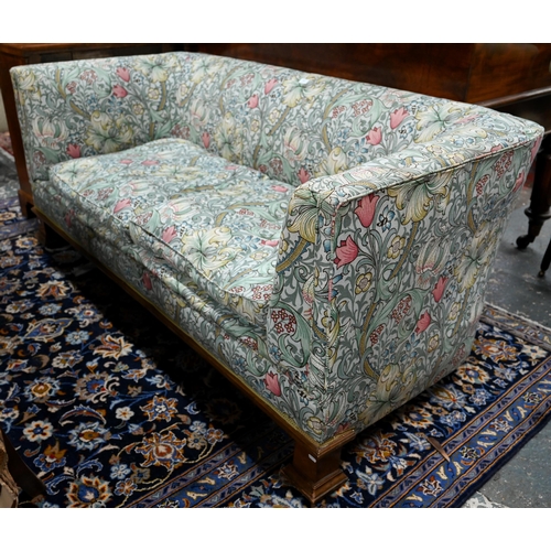 922 - An Arts & Crafts period Liberty style sofa, well upholstered in piped William Morris fabric, wit... 