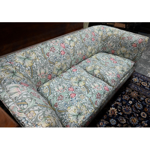 922 - An Arts & Crafts period Liberty style sofa, well upholstered in piped William Morris fabric, wit... 