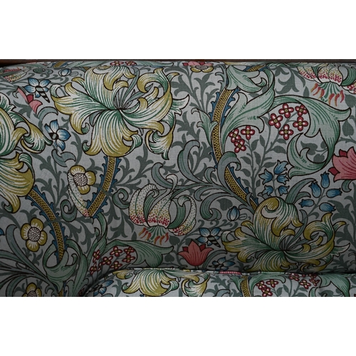 922 - An Arts & Crafts period Liberty style sofa, well upholstered in piped William Morris fabric, wit... 