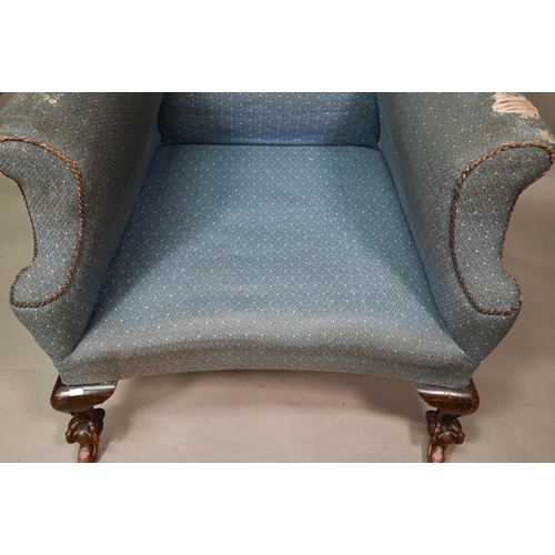 924 - A traditionally upholstered Queen Anne style wing armchair, with concave seat front, raised on short... 