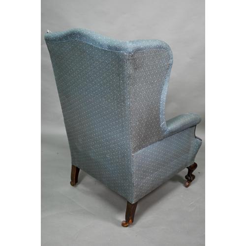 924 - A traditionally upholstered Queen Anne style wing armchair, with concave seat front, raised on short... 