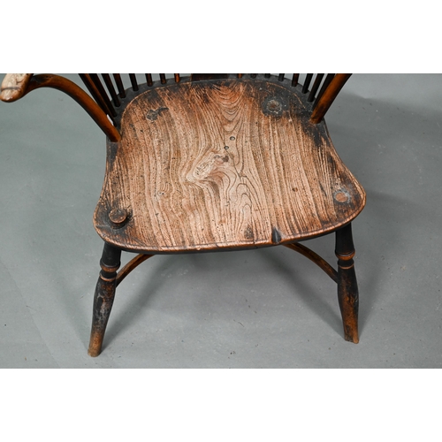 933 - A 19th century yew and elm seat Windsor stick-back elbow chair, the arms carved with various student... 