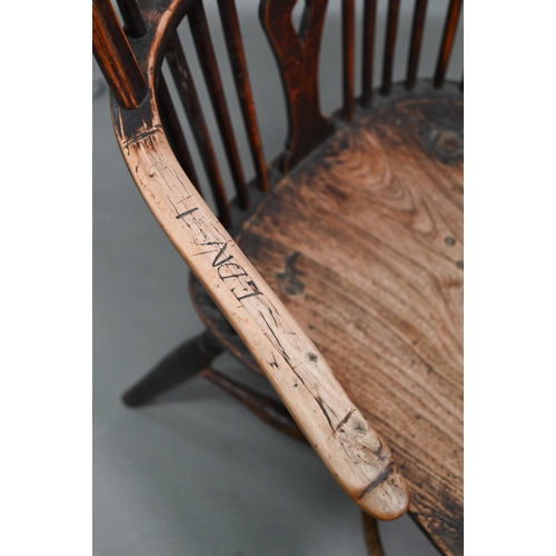 933 - A 19th century yew and elm seat Windsor stick-back elbow chair, the arms carved with various student... 