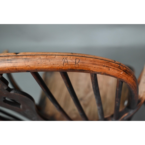 933 - A 19th century yew and elm seat Windsor stick-back elbow chair, the arms carved with various student... 