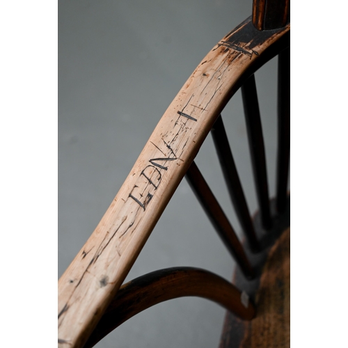 933 - A 19th century yew and elm seat Windsor stick-back elbow chair, the arms carved with various student... 