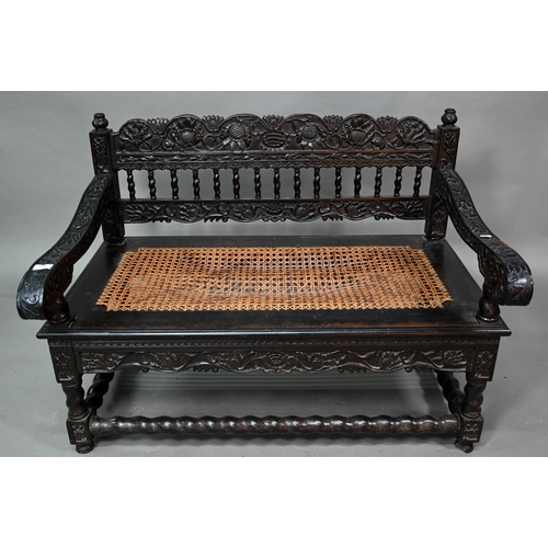 934 - A profusely carved and moulded colonial ebonised hardwood sofa bench, with cane panelled seat (with ... 