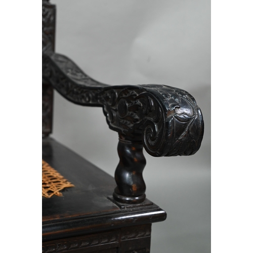 934 - A profusely carved and moulded colonial ebonised hardwood sofa bench, with cane panelled seat (with ... 