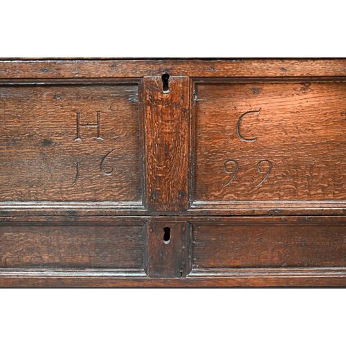 938 - A small oak mule chest, the two plank top over a twin panel front carved 'H C 1699', over a and full... 