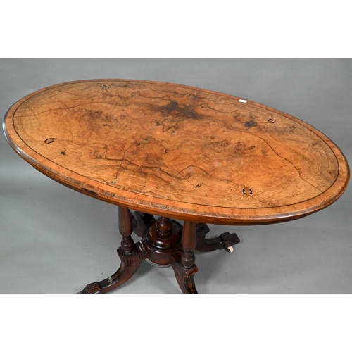 956 - A Victorian inlaid figured walnut centre table, the oval top raised on four to swept legs, on castor... 