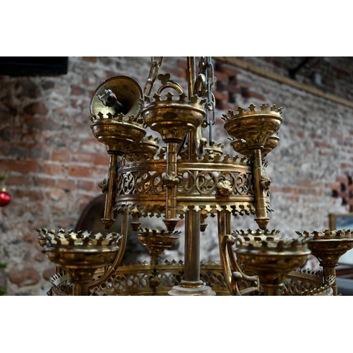 957 - A Gothic brass hanging circular two graduated tier candelabra, of ecclesiastical form, late 19th cen... 