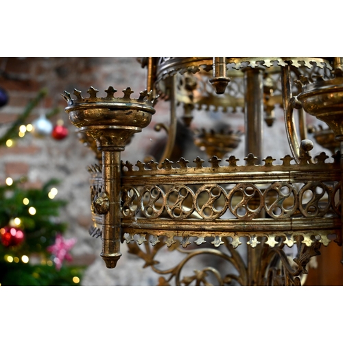 957 - A Gothic brass hanging circular two graduated tier candelabra, of ecclesiastical form, late 19th cen... 