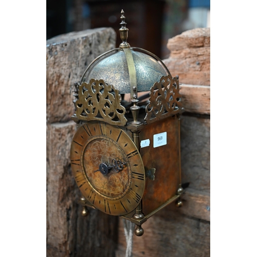 969 - An antique brass thirty hour lantern clock with dome bell to the top, the engraved dial with a singl... 