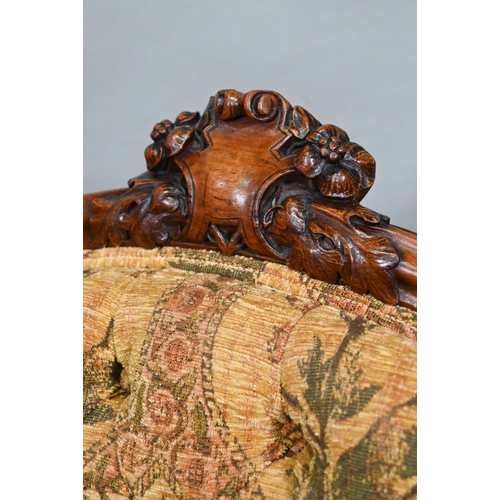 850A - A Victorian walnut framed open armchair with carved crest, deep buttoned back and stuff-over seats, ... 