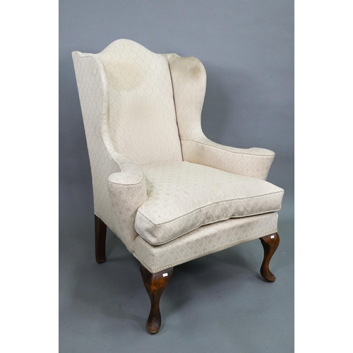 923A - A late 19th century wing armchair in the George II style, with out-swept arms, raised on walnut cabr... 