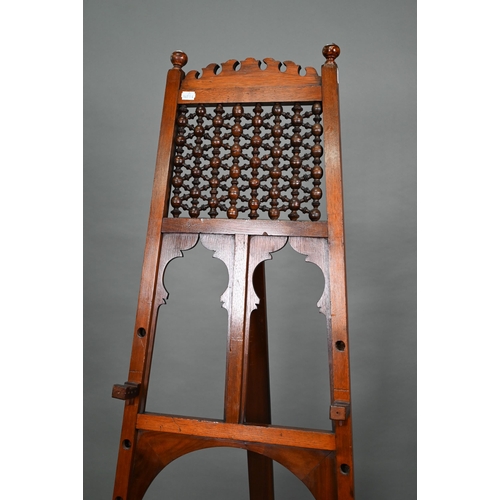 874A - An Edwardian pictue easel in the Liberty manner, with shaped frame, strut back and decorative 'spind... 