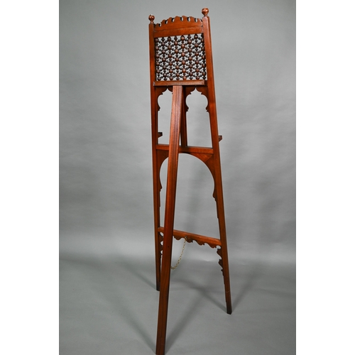 874A - An Edwardian pictue easel in the Liberty manner, with shaped frame, strut back and decorative 'spind... 