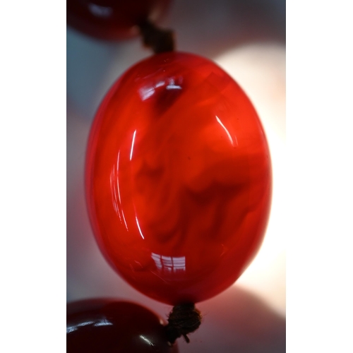 297 - A facetted orange amber graduated necklace, 54.1g; a cherry red amber graduated necklace, 50.4g; a r... 