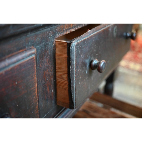 901 - An 18th century oak three drawer low dresser, very dark surface finish, raised on three turned front... 