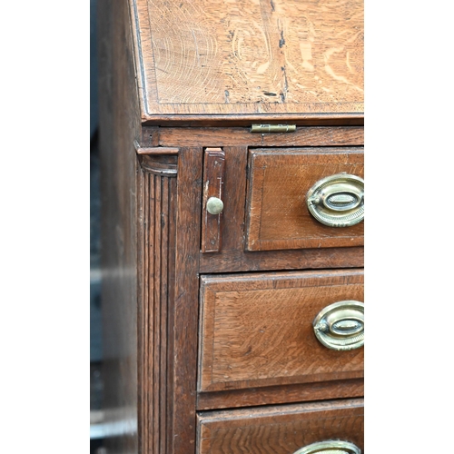 4 - An 18th century oak bureau cabinet, the upper part with pair of panelled doors enclosing shelves, th... 