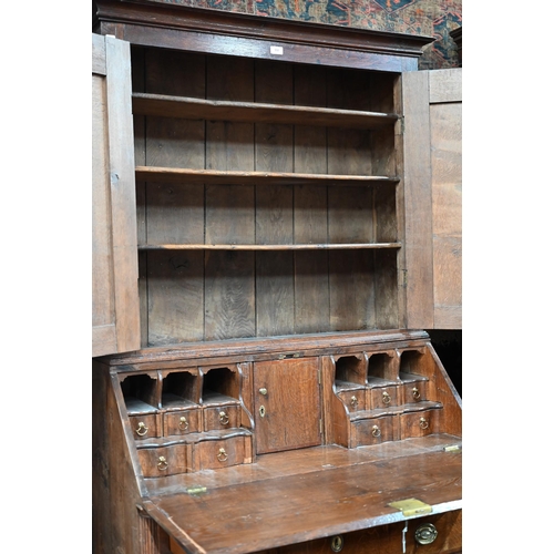 4 - An 18th century oak bureau cabinet, the upper part with pair of panelled doors enclosing shelves, th... 