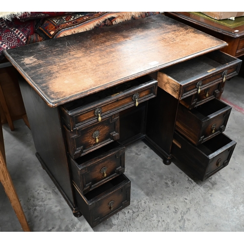 14 - An early 20th century oak Jacobean style kneehole desk, eight drawers around central niche with rece... 