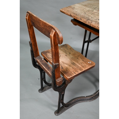 17 - A Victorian cast iron and oak student/school desk, the slope top carved with multiple graffiti, rais... 