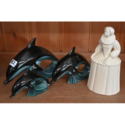 533 - A Poole pottery figure of Queen Elizabeth I, 24 cm, to/w a graduated set of three Poole dolphins (4)